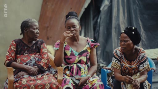 Trois femmes africaines assises côte à côte lors d'une discussion communautaire, illustrant les défis sociaux et économiques locaux.