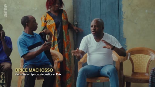 Brice Mackosso, membre de la Commission épiscopale Justice et Paix, s'exprime lors d'une discussion de groupe. Il est filmé en plan moyen dans un cadre informel, illustrant des enjeux de société ou de droits humains.