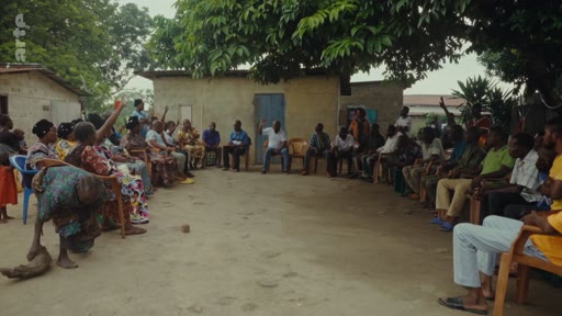 Des villageois sont réunis en cercle lors d'une assemblée en extérieur pour discuter de questions communautaires, illustrant des enjeux de médiation ou de litiges locaux.