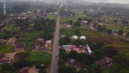 Vue aérienne plongeante montrant une route goudronnée rectiligne traversant un paysage rural parsemé de maisons et de végétation, illustrant le développement territorial et l'aménagement du paysage dans le Sud global.