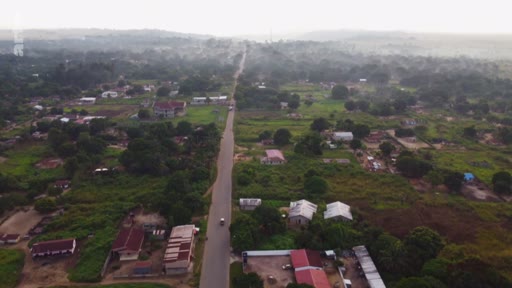 Vue aérienne d'une route rectiligne traversant un paysage rural avec des habitations dispersées, illustrant les enjeux de l'aménagement du territoire et de l'accaparement des terres dans le Sud global.
