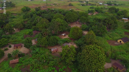 Vue aérienne d'un village rural isolé situé dans une zone de végétation dense, illustrant les conditions de vie dans les régions rurales du Sud global.