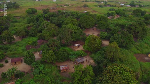 Vue aérienne d'un village rural isolé situé dans une zone de végétation dense, illustrant les conditions de vie dans les régions rurales du Sud global souvent touchées par l'accaparement des terres.