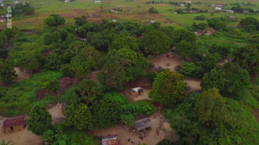 Vue aérienne d'un village rural situé dans une zone boisée, illustrant les conditions de vie et l'habitat dans le cadre d'un reportage sur l'accaparement des terres dans le Sud global.