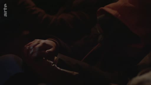 Gros plan sur deux mains qui se tiennent dans l'obscurité, illustrant la solidarité et le soutien émotionnel dans le contexte de la crise des réfugiés.