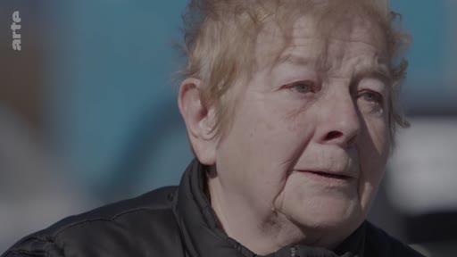 Gros plan sur une femme âgée s'exprimant face caméra, illustrant un témoignage sur le vécu des civils lors d'un conflit armé. L'image est extraite d'un reportage diffusé sur Arte.