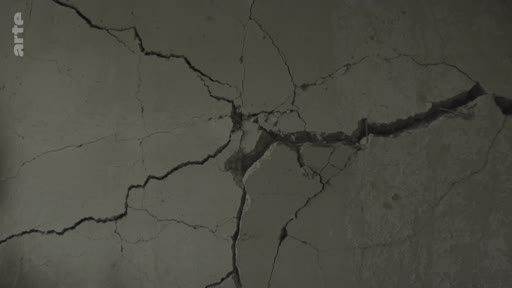 Gros plan sur un mur en béton lourdement fissuré, illustrant les destructions causées par la guerre en Ukraine dans la ville de Mykolaiv.