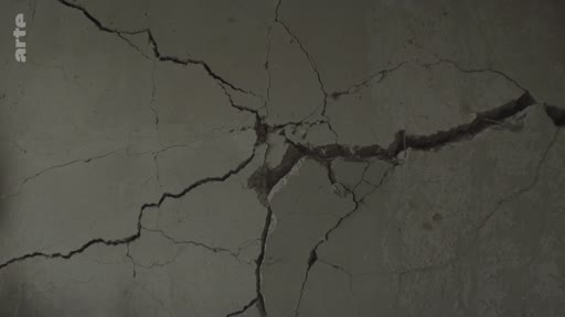 Gros plan sur un mur en béton lourdement fissuré, illustrant les destructions et les dommages structurels causés par les bombardements à Mykolaïv, en Ukraine.