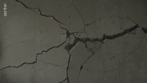 Gros plan sur un mur en béton lourdement fissuré, illustrant les destructions urbaines causées par les bombardements à Mykolaiv, en Ukraine.