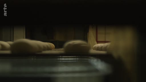 Vue en gros plan de pâtons de pain crus circulant sur une ligne de production automatisée dans une boulangerie industrielle près de la ligne de front.