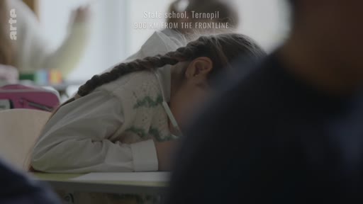 Une jeune élève avec des tresses est assise à son bureau dans une école publique de Ternopil, en Ukraine, lors d'une séance de pleine conscience en classe. L'image illustre le quotidien des enfants ukrainiens dans le contexte du conflit actuel.