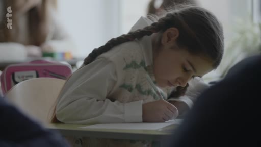 Une jeune fille avec des tresses est assise à son bureau dans une salle de classe, écrivant attentivement sur une feuille de papier lors d'une séance de pleine conscience. L'ambiance est calme et studieuse, illustrant les pratiques de bien-être et de concentration à l'école.