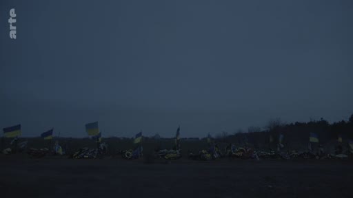 Vue d'ensemble de tombes ou d'un mémorial improvisé marqué par de nombreux drapeaux ukrainiens, illustrant les conséquences de la guerre en Ukraine.