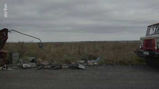 Un camion stationné sur le bord d'une route dans la région de Kherson, en Ukraine, à proximité d'un amas de débris et de détritus, illustrant les conséquences de la guerre dans la zone.