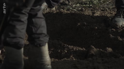 Des personnes travaillent sur un site d'exhumation, creusant le sol pour des recherches médico-légales ou archéologiques.