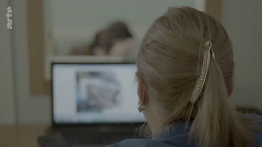 Une personne vue de dos consulte des documents numériques sur un ordinateur portable, dans le cadre d'une procédure d'identification de victimes au sein d'un institut médico-légal.