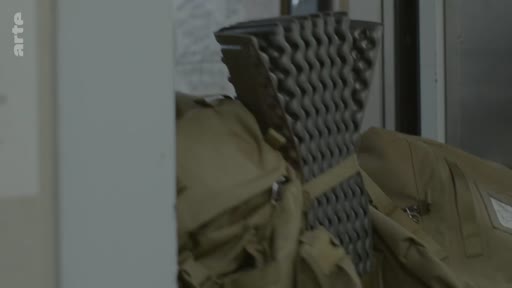 Un sac à dos de type militaire et un tapis de sol en mousse plié, symbolisant le retour d'un soldat à son domicile.
