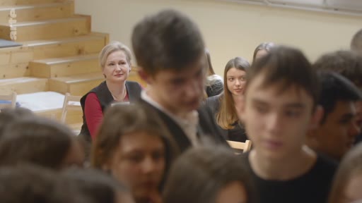 Une enseignante assiste à un échange entre ses élèves dans une salle de classe, observant attentivement les interactions du groupe.