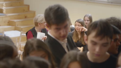 Une enseignante discute avec un groupe d'élèves dans une salle de classe, favorisant les échanges et la participation des jeunes.