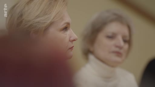 Deux femmes, dont l'une est au premier plan, assistent à une discussion ou une conférence, illustrant le thème de la réflexion et de l'écoute dans le documentaire sur l'éthique du rêve en temps de guerre.