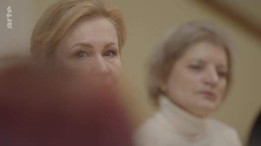 Deux femmes, dont l'une au premier plan, assistent à une discussion ou une conférence, dans le cadre d'un reportage sur l'éthique et le rêve en temps de guerre.