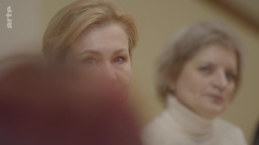 Deux femmes, dont l'une est au premier plan, participent à une discussion ou une conférence dans le cadre d'un reportage sur l'éthique du rêve en temps de guerre.