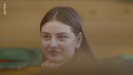 Gros plan sur une jeune femme en pleine réflexion, le menton appuyé sur sa main, dans une séquence illustrant l'engagement personnel.