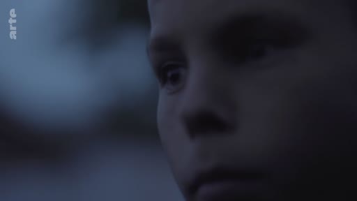 Gros plan sur le visage d'un enfant, filmé dans une lumière tamisée et bleutée, évoquant une atmosphère mélancolique ou introspective.