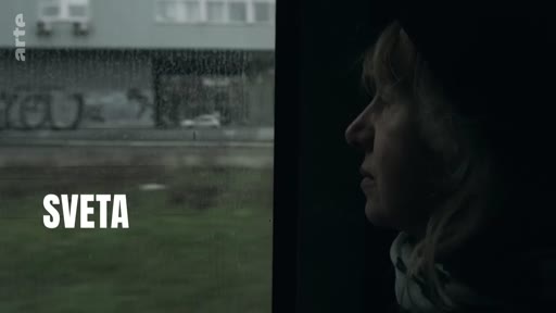 Une femme nommée Sveta regarde par la fenêtre d'un train, observant le paysage défiler lors de son voyage vers une nouvelle vie.
