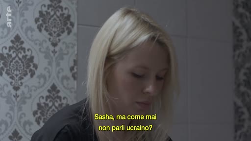 Une jeune femme blonde, identifiée comme Sasha, est filmée en gros plan lors d'une interview. Un sous-titre en italien pose la question de savoir pourquoi elle ne parle pas ukrainien, soulignant les enjeux linguistiques et identitaires en Ukraine.