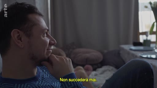 Un homme, vu de profil, exprime une réflexion lors d'une discussion sur la menace de guerre, avec le sous-titre 'Non succederà mai' affiché à l'écran.