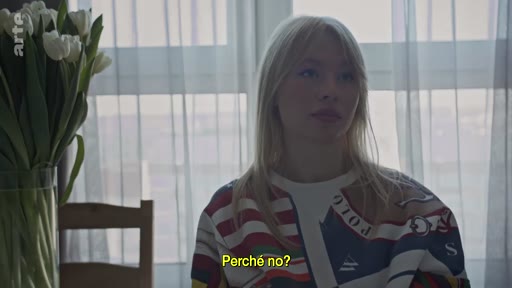 Une jeune femme blonde, vêtue d'un pull à motifs, est filmée en plan moyen lors d'une interview. Elle discute de la menace imminente de guerre, comme l'indique le sous-titre « Perché no? ».