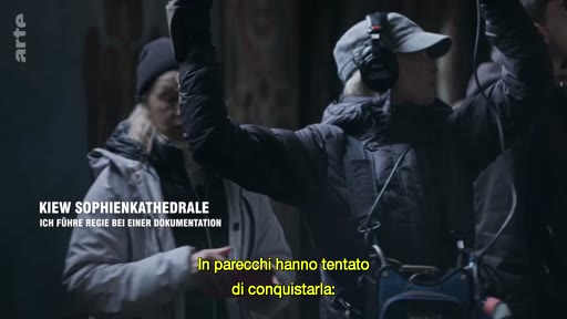 Une équipe de tournage, incluant une réalisatrice avec un casque audio, filme un documentaire à l'intérieur de la cathédrale Sainte-Sophie à Kiev. Le texte à l'écran mentionne le lieu et le contexte de la réalisation.