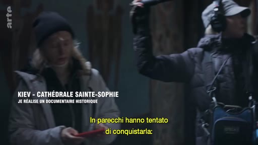 Une équipe de tournage, composée d'une réalisatrice et d'un ingénieur du son, travaille à l'intérieur de la cathédrale Sainte-Sophie à Kiev pour un documentaire historique. Le texte à l'écran précise le lieu et le contexte de la production.
