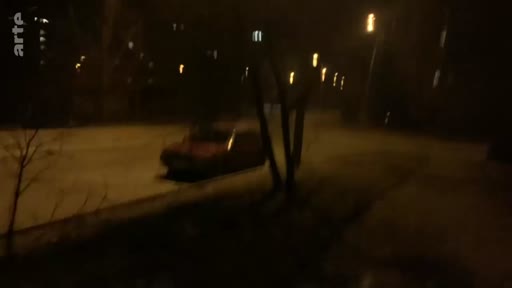 Une voiture roule dans une rue sombre et déserte, illustrant l'atmosphère nocturne durant les premiers jours de l'invasion en Ukraine.