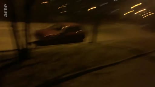 Une voiture roule dans une rue sombre et peu éclairée, illustrant l'atmosphère nocturne durant les premiers jours de l'invasion.