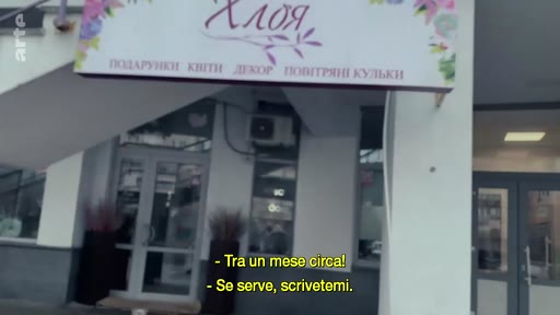 Une devanture de boutique nommée 'ХЛОЯ' proposant des fleurs, des cadeaux et de la décoration, située en Ukraine. Le texte sur la devanture indique 'ПОДАРУНКИ КВІТИ ДЕКОР ПОВІТРЯНІ КУЛЬКИ'.