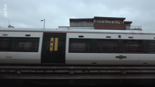 Un train de banlieue circule sur un viaduc, illustrant le transport ferroviaire urbain dans le cadre d'un reportage sur les parcours de réfugiés.