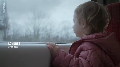 Une jeune enfant observe le paysage par la fenêtre d'un train lors d'un voyage vers Londres en avril 2022. L'image illustre le thème du voyage et de la mobilité.