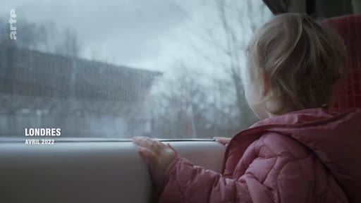 Une jeune enfant observe le paysage à travers la vitre d'un train lors d'un voyage à Londres en avril 2022.