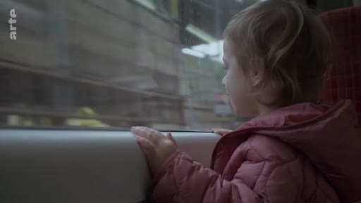 Une petite fille observe le paysage défiler depuis la fenêtre d'un train, illustrant un voyage en train avec un enfant.