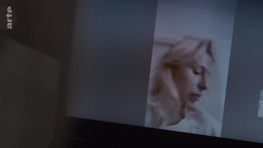 Une femme blonde est filmée en gros plan alors qu'elle regarde son écran d'ordinateur, dans une scène évoquant la routine domestique et les réflexions personnelles.