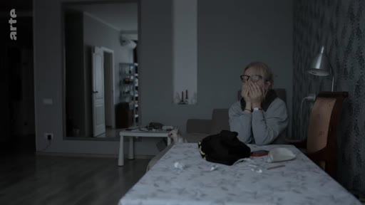 Une femme portant des lunettes est assise à une table dans une pièce sombre, les mains jointes devant son visage, dans une atmosphère mélancolique ou préoccupée. Le logo de la chaîne Arte est visible dans le coin supérieur gauche.