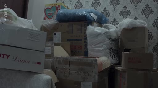 Des cartons de déménagement et des sacs plastiques sont empilés dans une pièce, évoquant un départ ou un changement de vie.