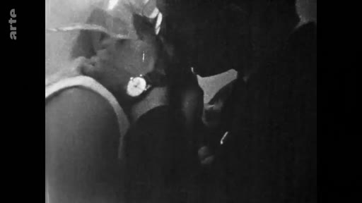 Une femme regarde des photographies anciennes, évoquant des souvenirs personnels et une nostalgie du passé dans une séquence d'archives.