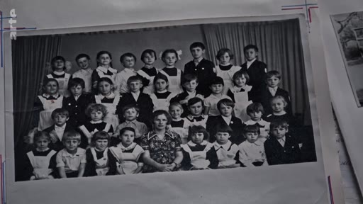Une photographie de classe d'archives en noir et blanc montrant un groupe d'élèves posant avec leur institutrice, typique de l'époque soviétique ou est-européenne.