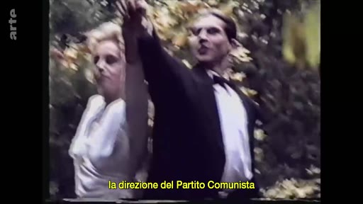Un homme en costume et une femme en robe blanche dansent ensemble dans un jardin, une image d'archives évoquant une époque passée. Le sous-titre mentionne la direction du Parti communiste.