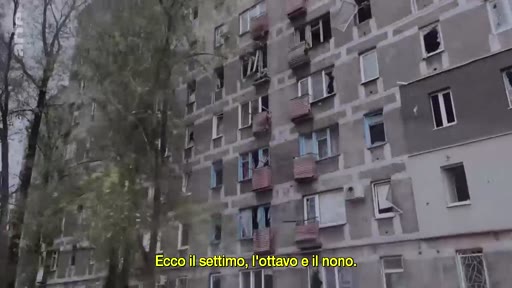 Vue extérieure d'un immeuble d'habitation gravement endommagé, avec des fenêtres brisées et des traces d'impacts, illustrant les destructions causées par la guerre en Ukraine. Le sous-titre mentionne les étages touchés.