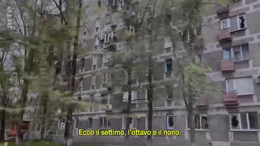 Un immeuble d'habitation en béton présentant des traces de destructions et des fenêtres brisées, témoignant des conséquences d'un conflit armé. L'image illustre la dégradation du paysage urbain suite à des attaques militaires.