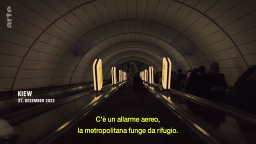 Le 31 décembre 2022 à Kiev, des civils se réfugient dans une station de métro utilisée comme abri anti-aérien lors d'une alerte. L'image montre les escaliers mécaniques de la station plongés dans une ambiance sombre et tendue.